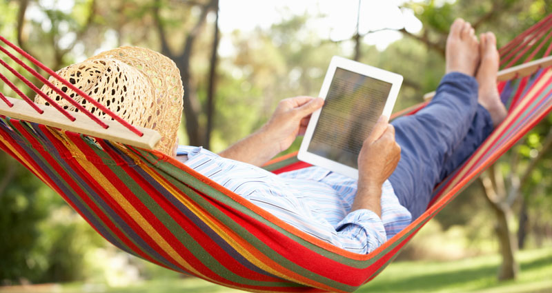 senior man on hammock with iPad