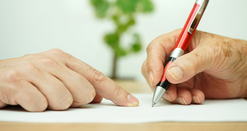 close-up of someone's hand filling out paperwork