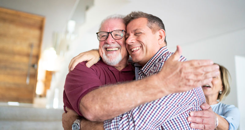 man hugging his senior father
