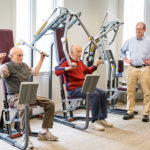 Two men exercising while staff member oversees