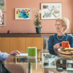 Two residents laughing and enjoying coffee in an apartment