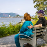 Woman and Man sitting on bench looking at scenic views from Kendal on the Hudson Walk Town