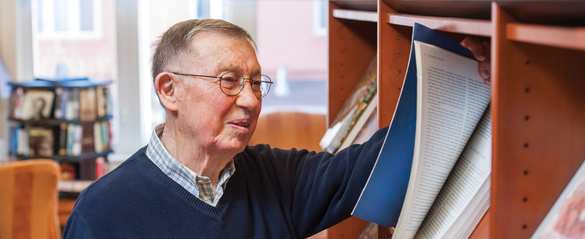 Senior man looking at magazines in the library