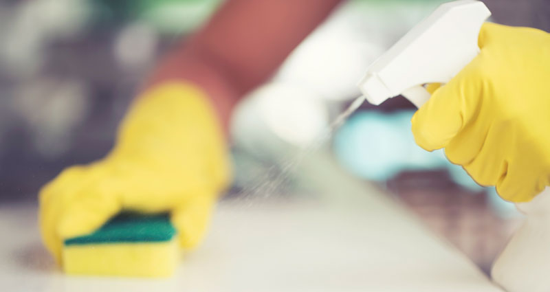 Close up image of wiping down a counter with gloves on