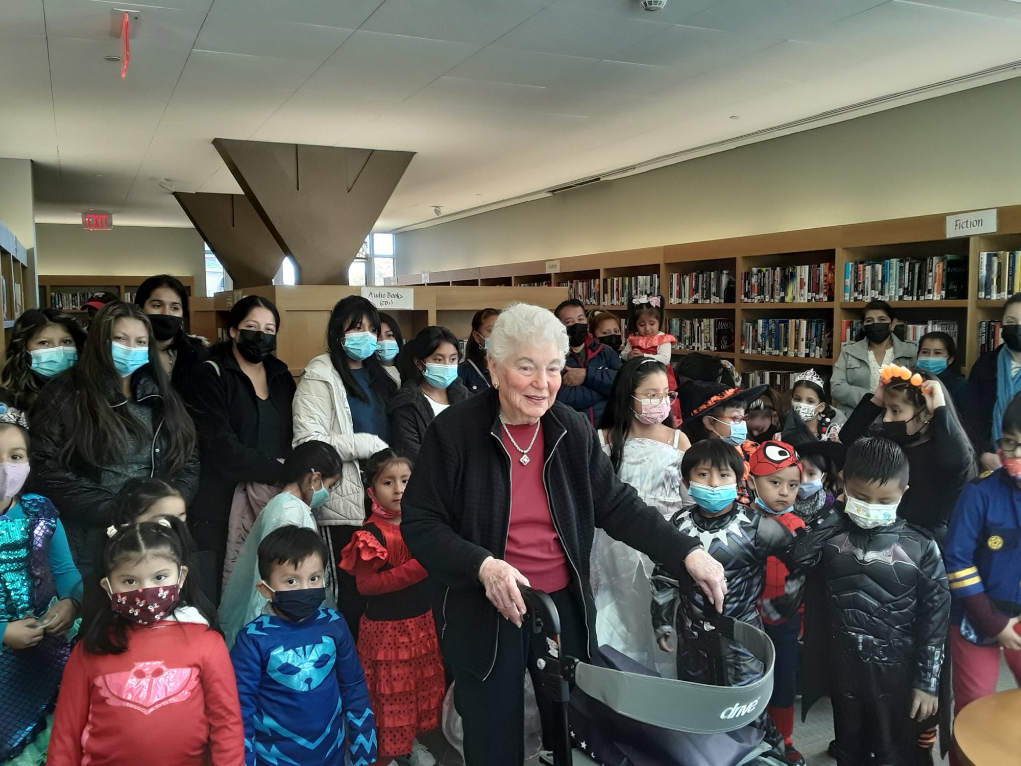 Senior woman at library with a group of children and their parents