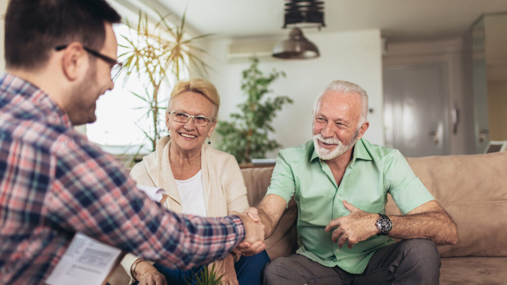 senior couple shaking hands with a representative after signing a contract