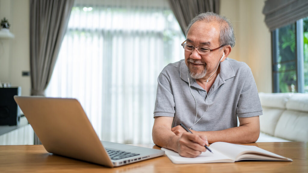 Home office of Senior man working online with laptop computer, gaining the benefits of learning a second language, Sleepy Hollow, NY.
