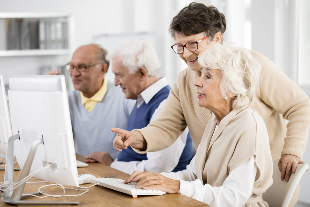 Elder lady with glasses helping her friend with learning, to get the benefits of learning a second language, Sleepy Hollow, NY.