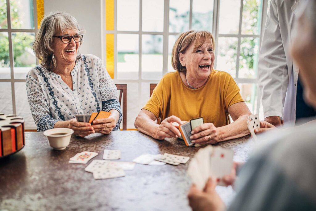 seniors laughing while playing a card game