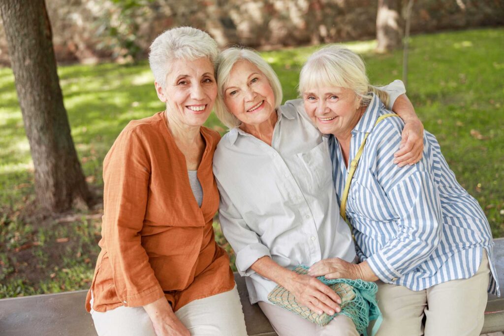 a group of senior friends sitting outside on a bench