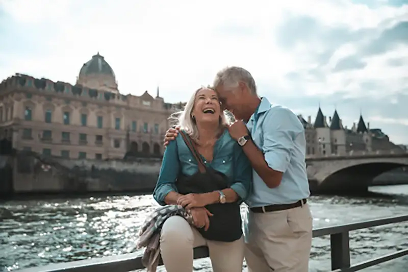 Senior couple laughing on vacation on a bridge over a waterway