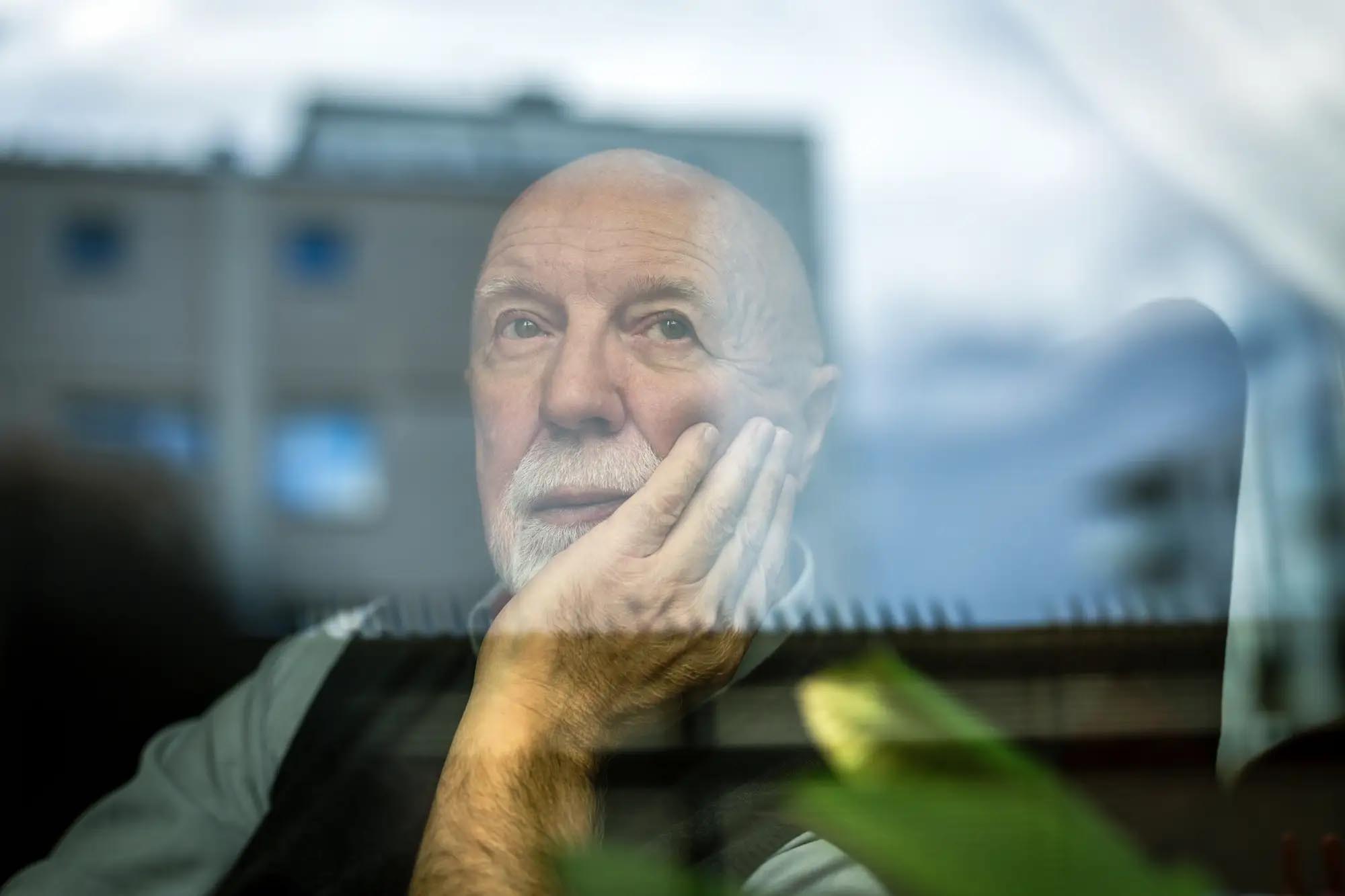 senior man looking out window